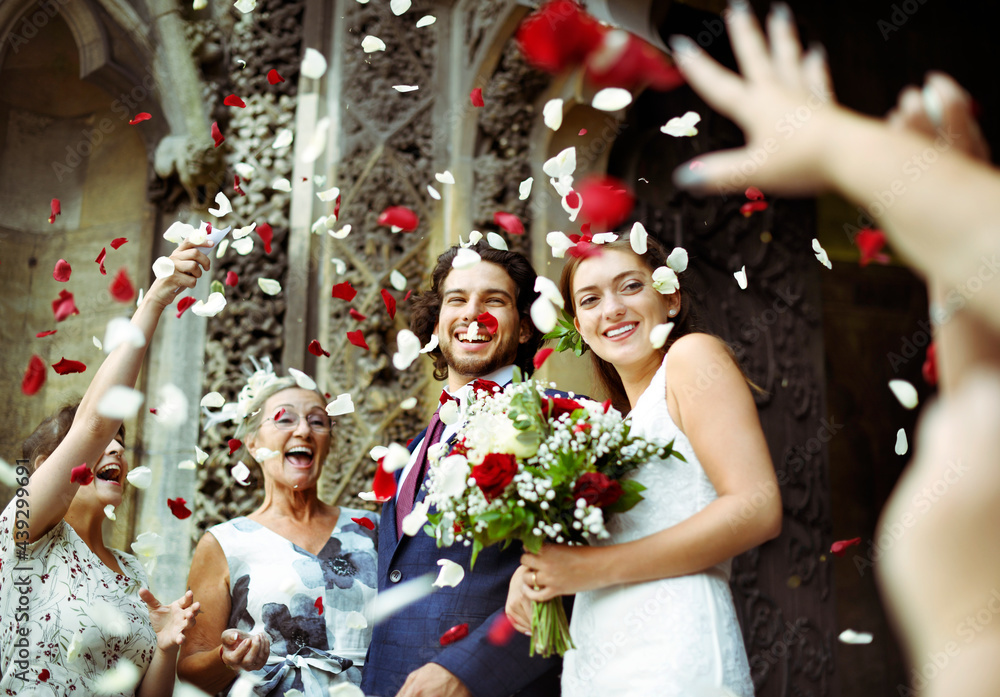 Family throwing rose petals at the newly wed bride and groom