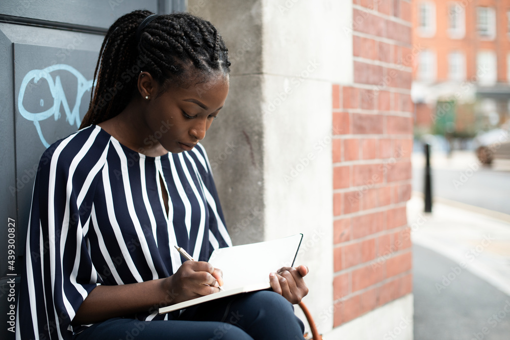 Woman sitting and taking notes in a doorway