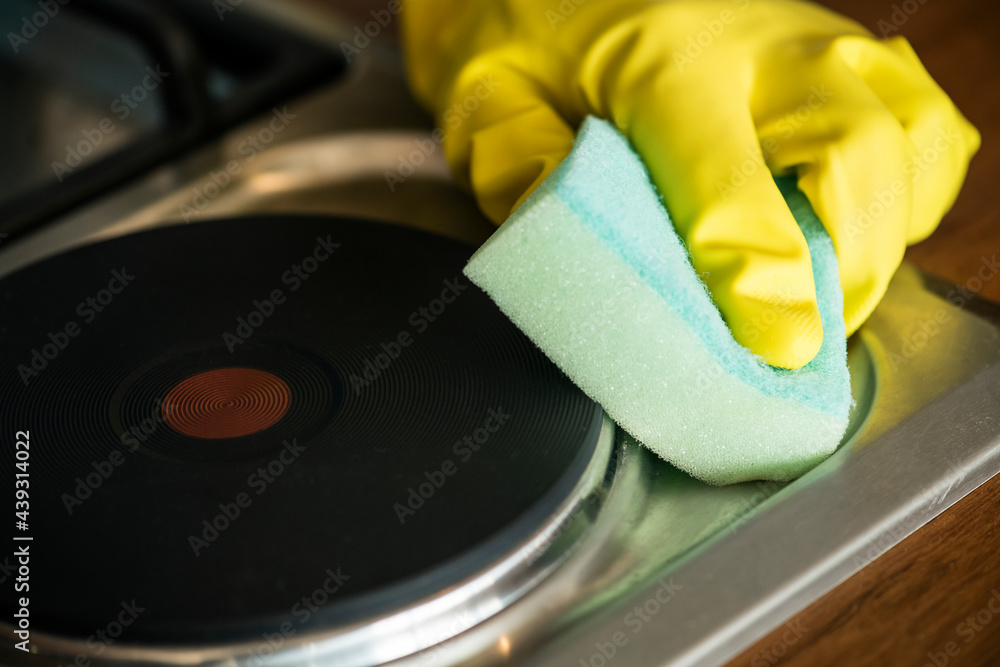 Closeup of hands wearing gloves wiping the stove domestic chores concept