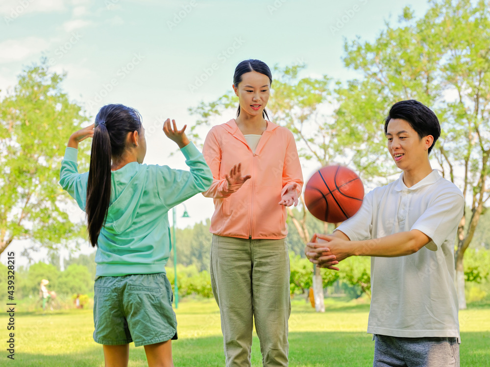 Happy family of three playing basketball in the park