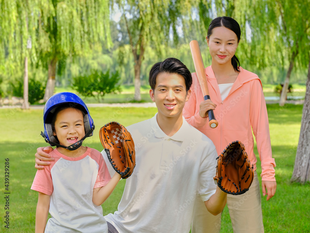 Happy family of three playing baseball in the park