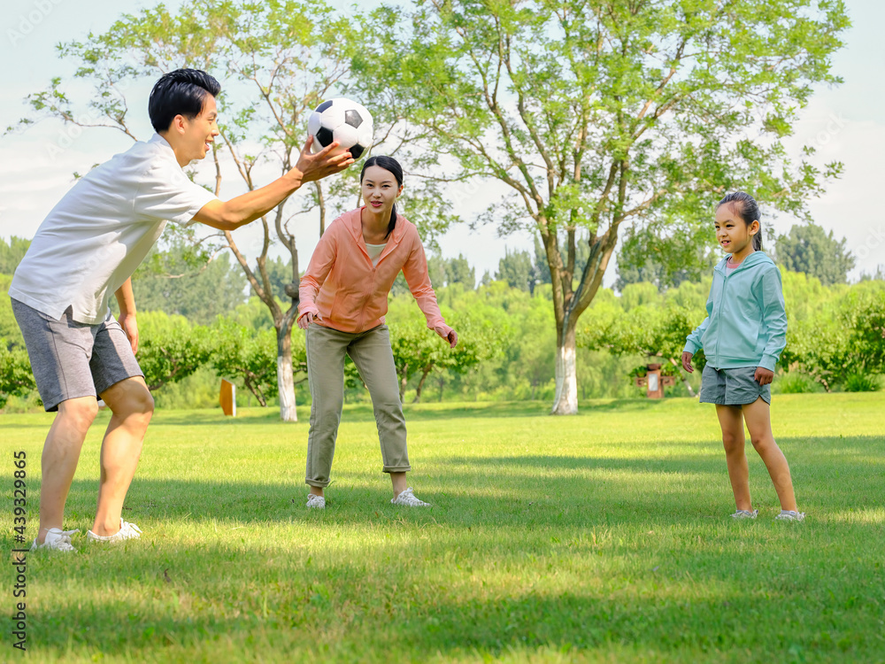 Happy family of three playing football in the park