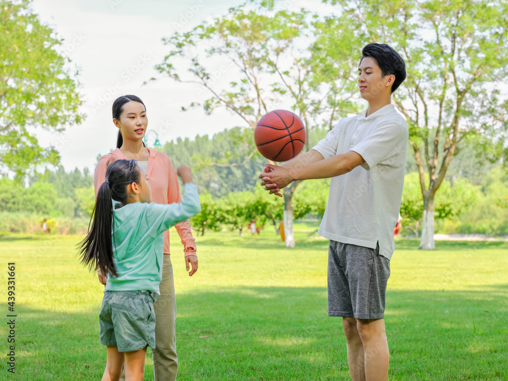 Happy family of three playing basketball in the park