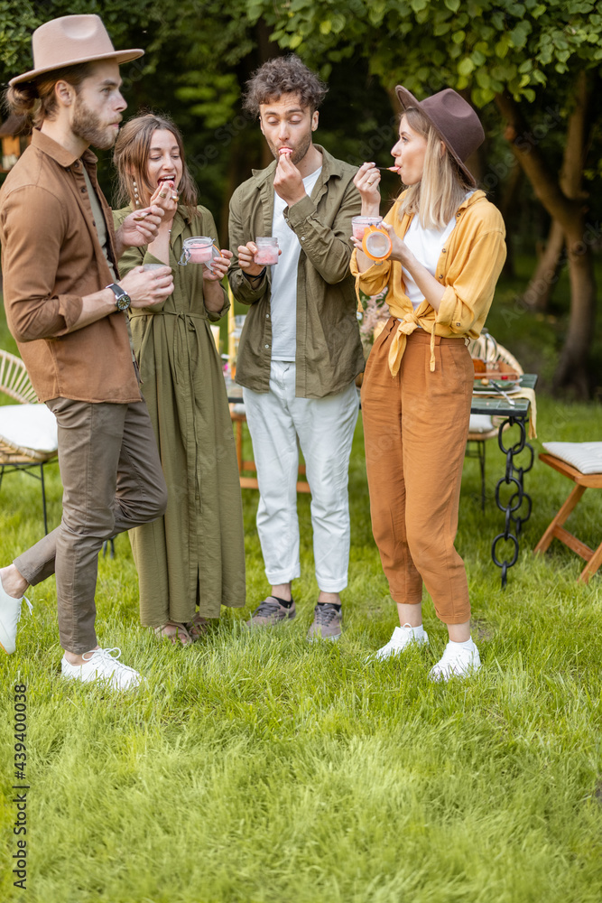 Group of young friends having fun together eating ice cream in glass jars during a festive snack nea