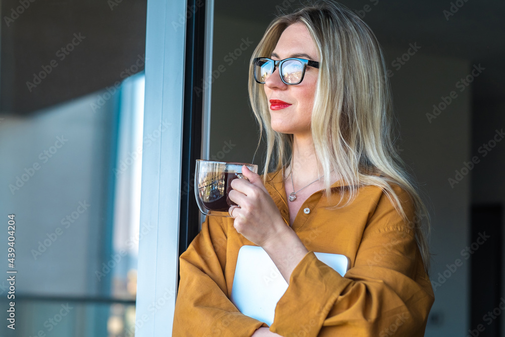 商务女性，拿着笔记本电脑的老师站在露台上。女孩在新鲜空气中喝咖啡，工作，st