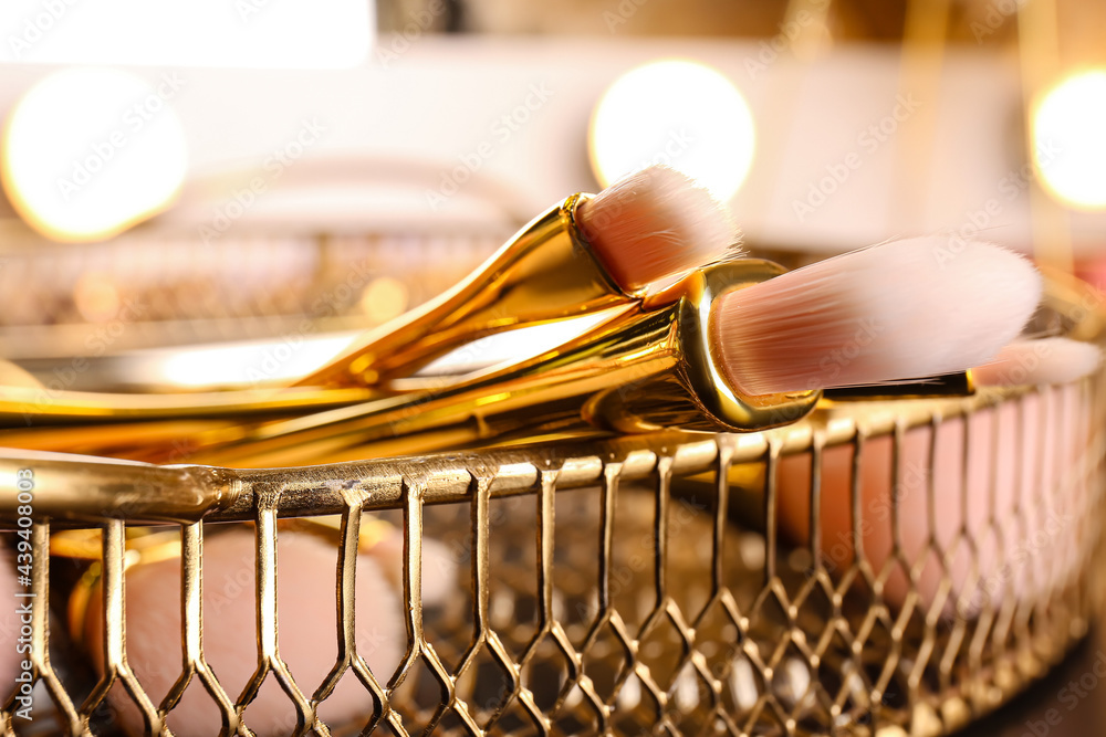 Tray with set of makeup brushes on table, closeup