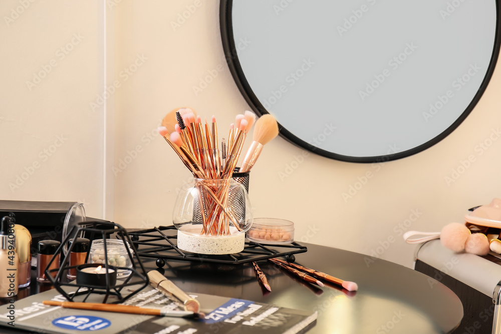 Set of makeup brushes and cosmetics on dressing table