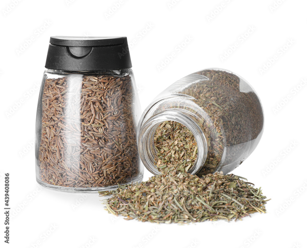 Jars with dried herbs and cumin on white background