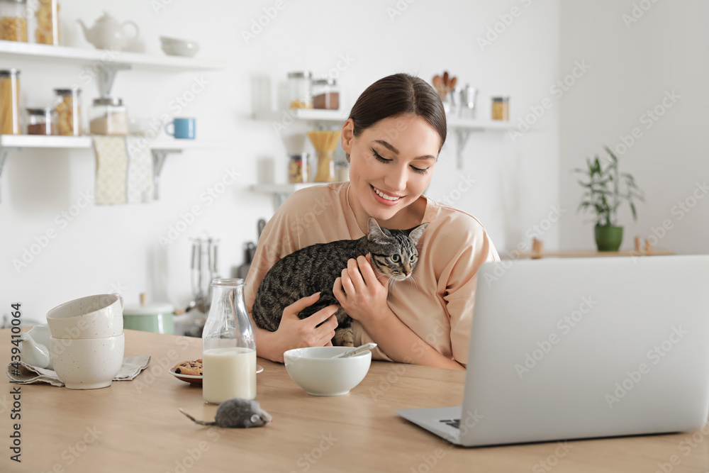 美丽的年轻女人和可爱的猫在厨房