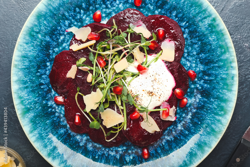 Plate with delicious beetroot carpaccio on dark background, closeup