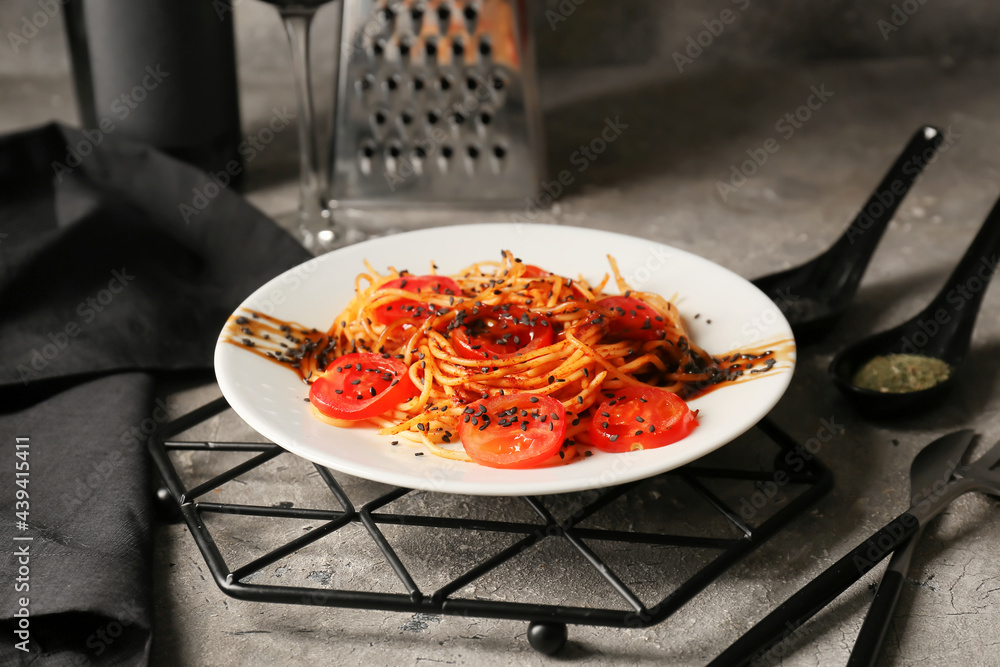 Plate with tasty pasta and tomatoes on dark background