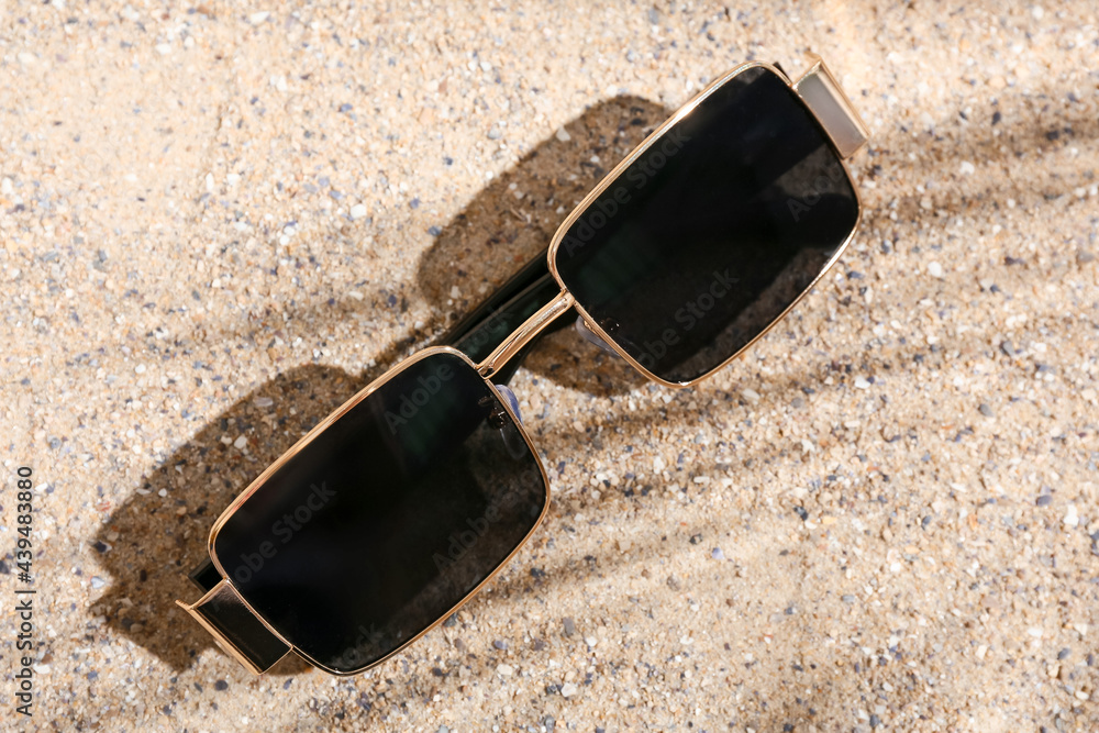 Stylish beach sunglasses on sand