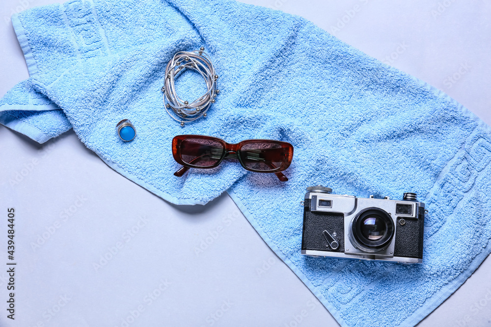 Stylish female accessories with towel and photo camera on light background