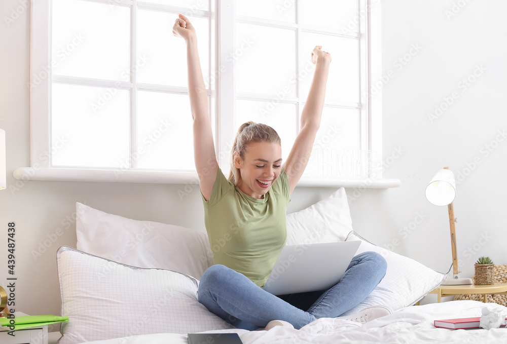 Happy female student with laptop at home