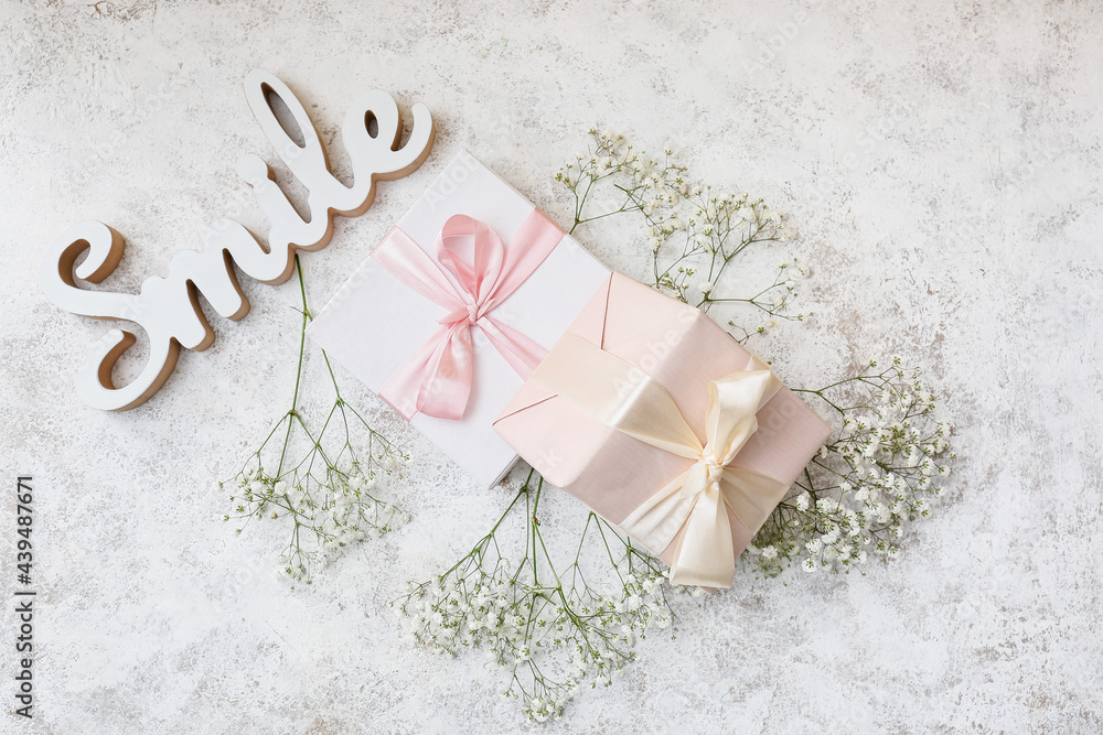 Composition with beautiful gypsophila flowers and present boxes on light background