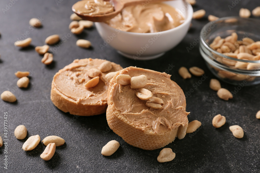 Bread with tasty peanut butter on dark background