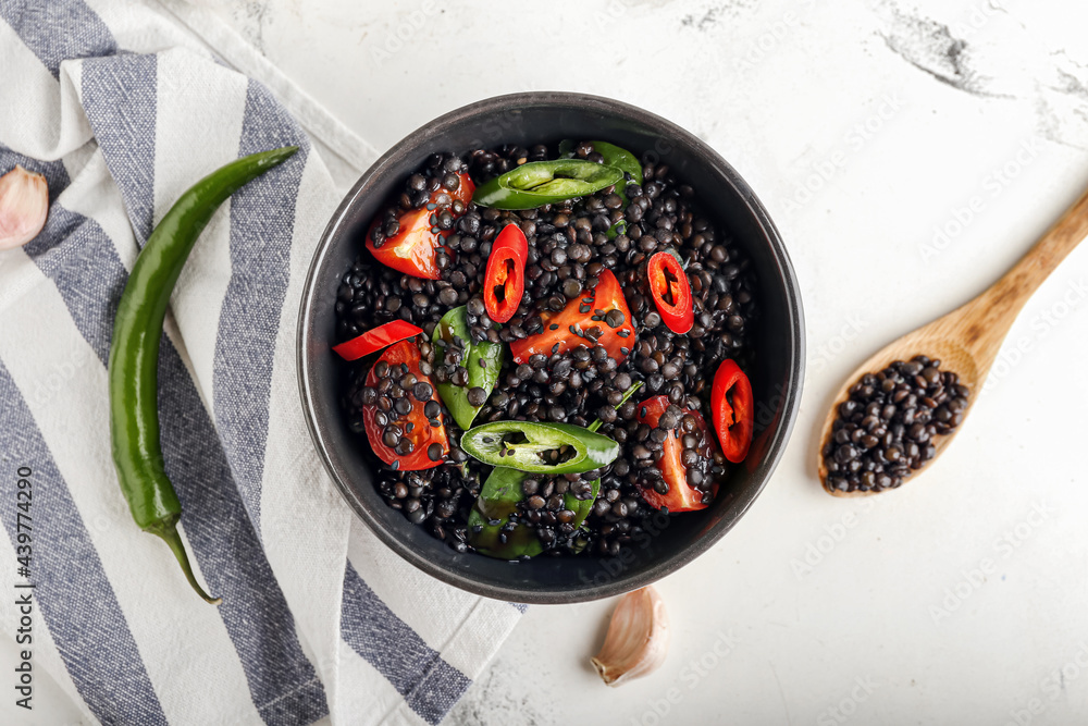 Bowl with tasty cooked lentils and vegetables on white background