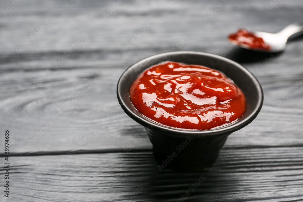 Bowl with tasty barbecue sauce on dark wooden background