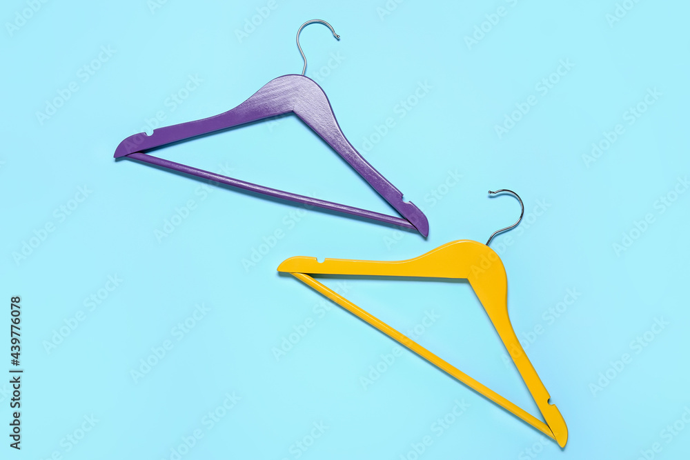 Stylish clothes hangers on color background