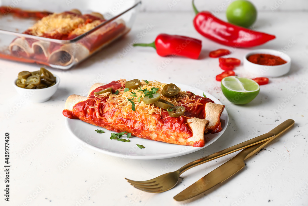 Plate with tasty cooked enchilada on white background