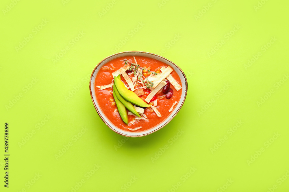 Bowl of tasty chicken enchilada soup on color background