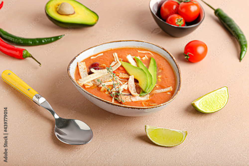 Bowl of tasty chicken enchilada soup on color background