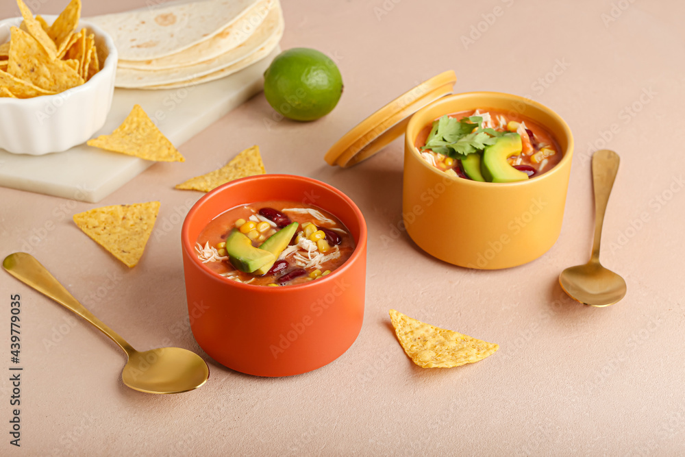 Bowls of tasty chicken enchilada soup on color background