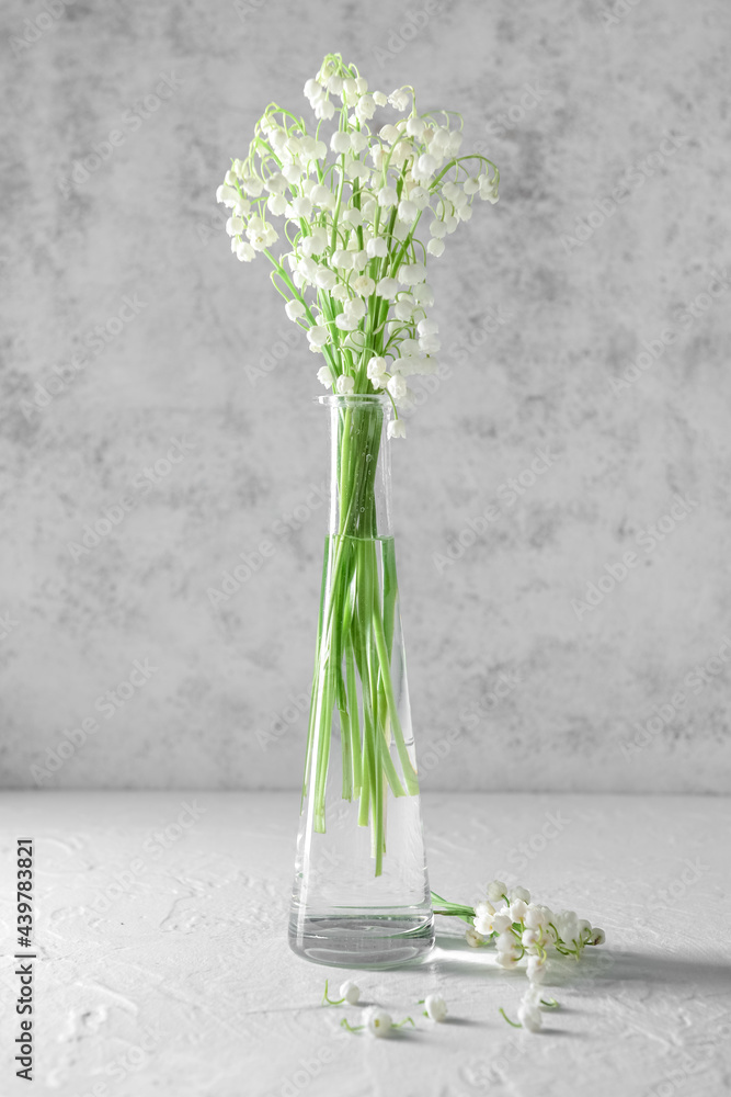 Vase with beautiful lily-of-the-valley flowers on light background