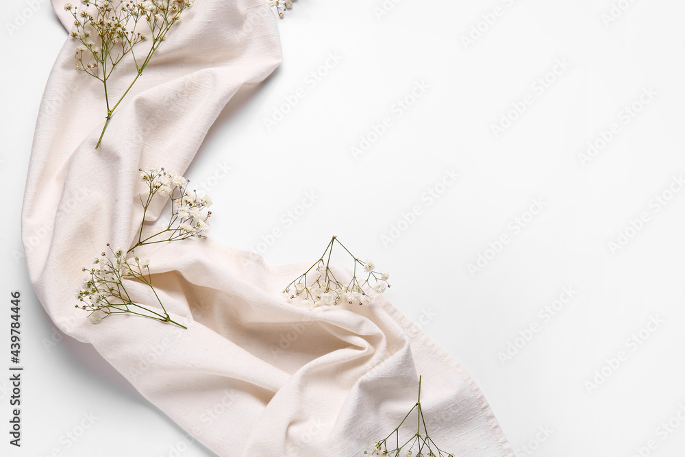 Beautiful gypsophila flowers and fabric on white background