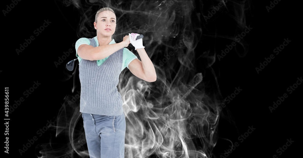 Caucasian female golf player swinging golf club against smoke effect on black background