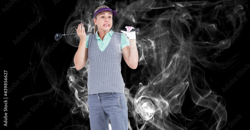 Caucasian female golf player holding golf club against smoke effect on black background