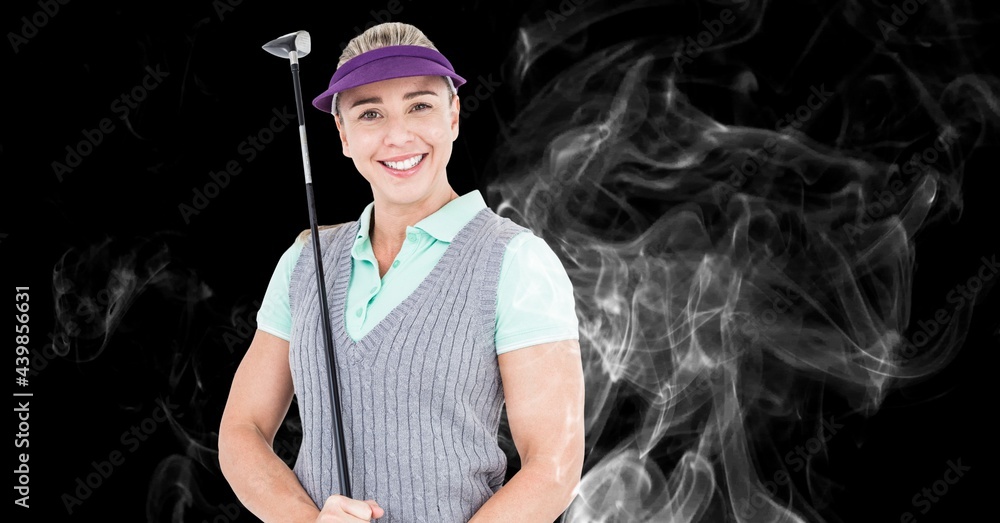 Portrait of caucasian female golf player holding golf club against smoke effect on black background