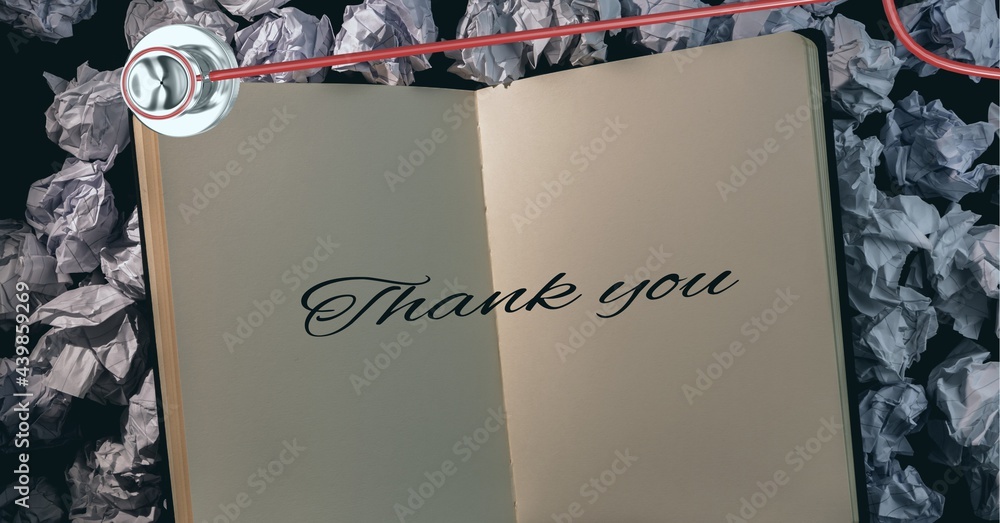 Thank you text and stethoscope over book against crumbled paper balls in background