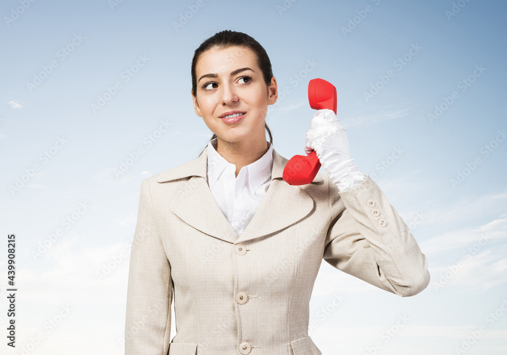 Attractive young woman holding red retro phone.