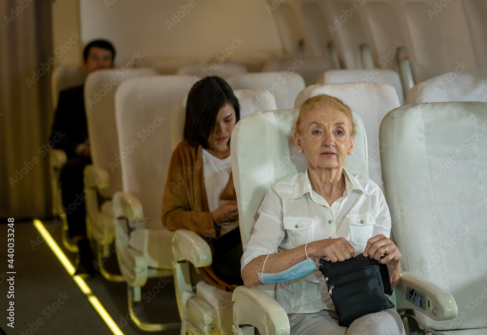 飞行中，商务飞机上坐在座位上的乘客老年妇女，旅行概念。