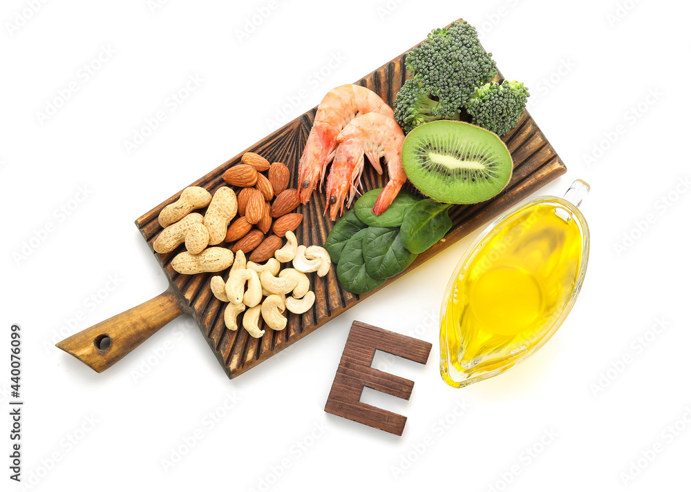 Board with healthy products rich in vitamin E on white background