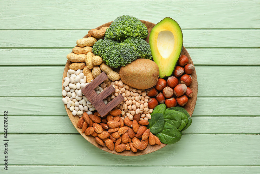 Plate with healthy products rich in vitamin E on color wooden background