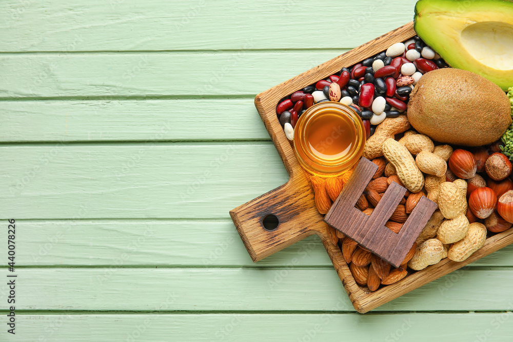 Board with healthy products rich in vitamin E on color wooden background