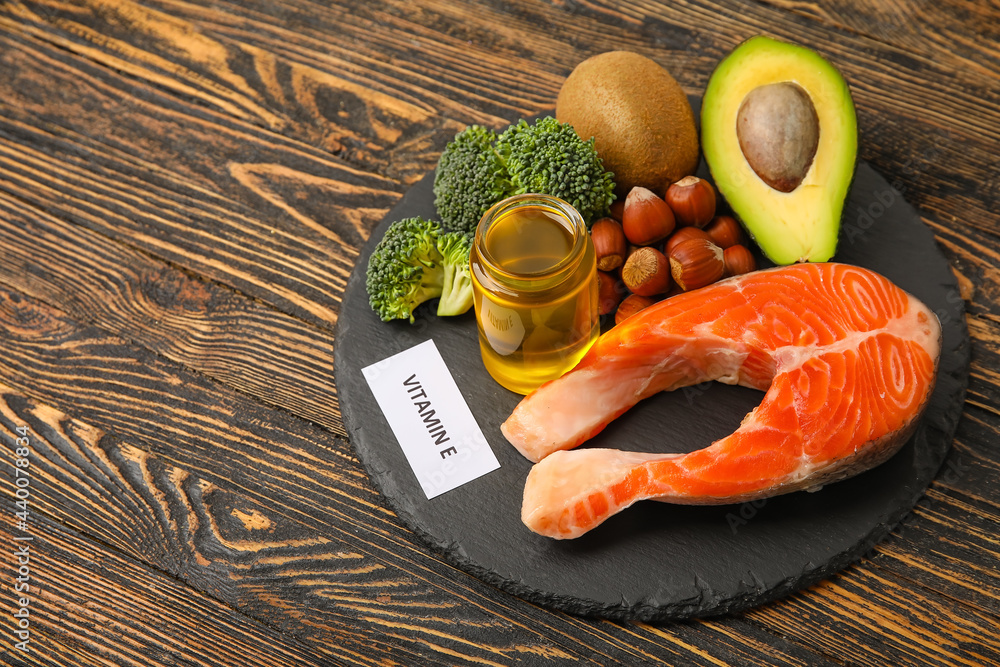 Slate plate with healthy products rich in vitamin E on wooden background