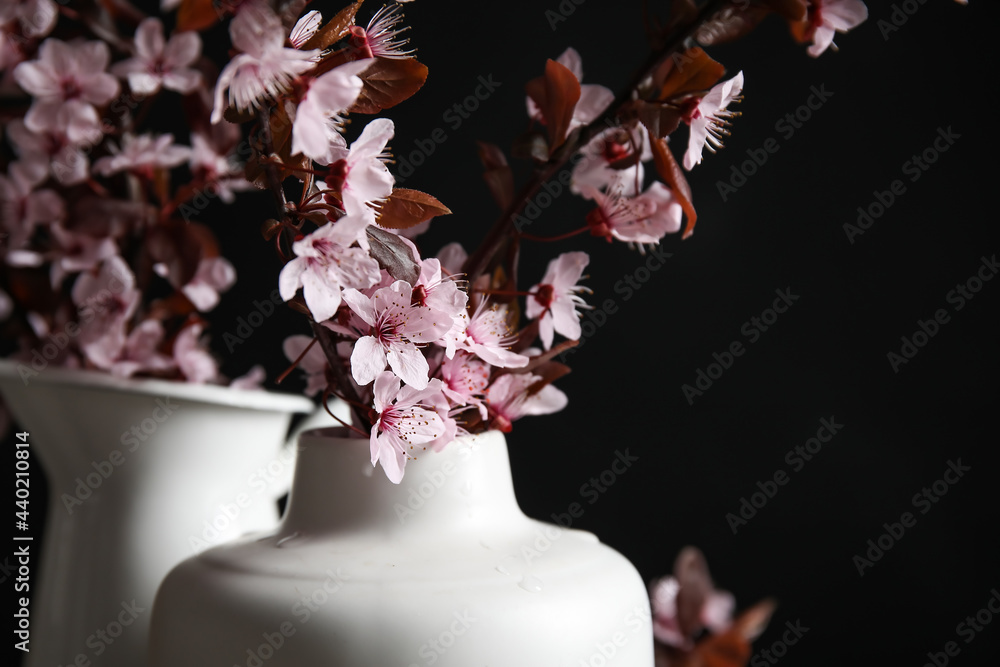 Vases with beautiful blossoming branches on dark background, closeup