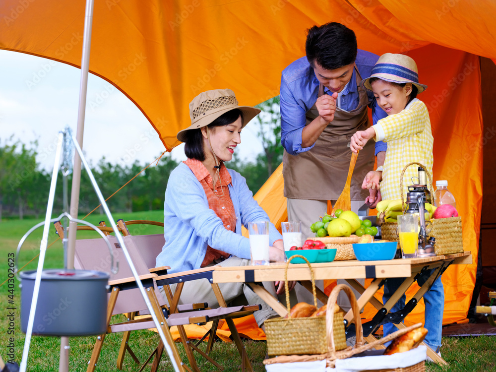 A happy family of three cooks outdoors