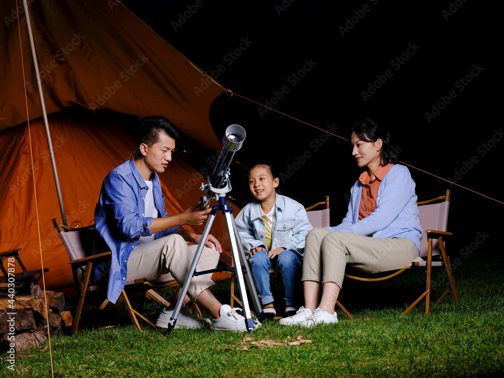 A happy family of three using telescopes outdoors