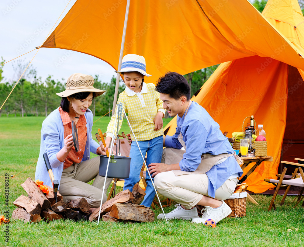 A happy family of three cooks outdoors