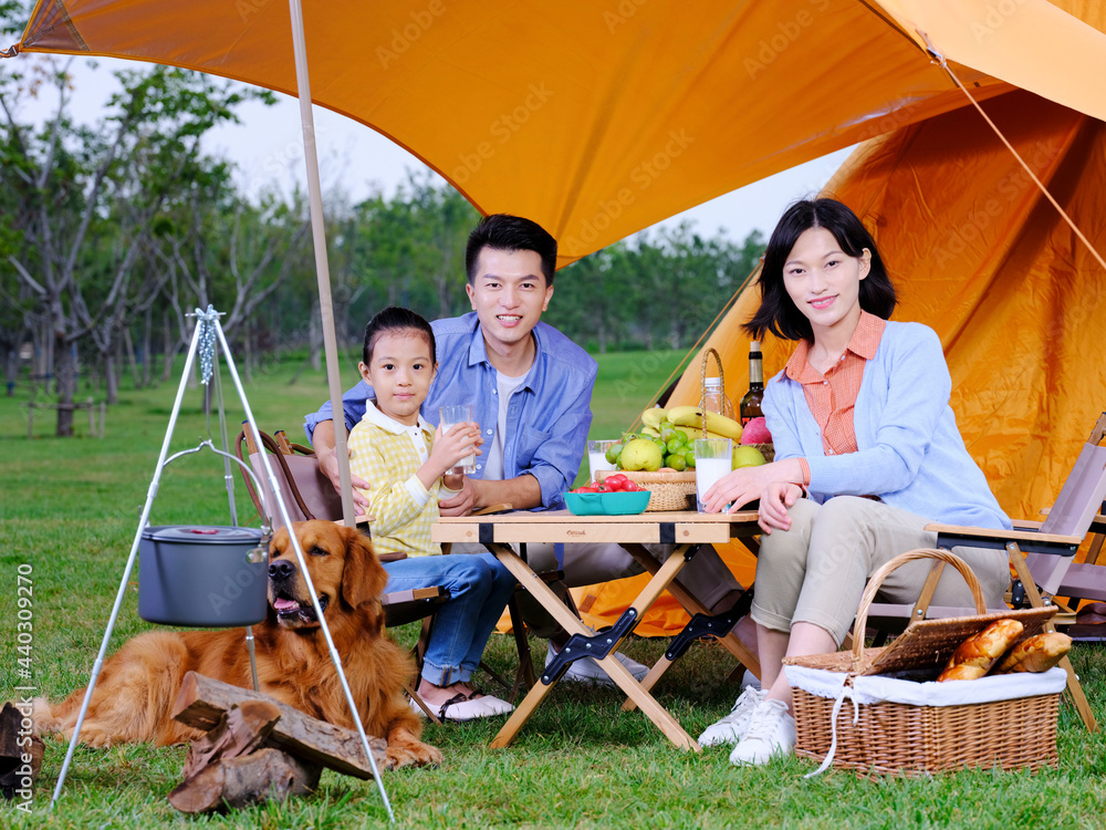 Happy family of three and dog camping out