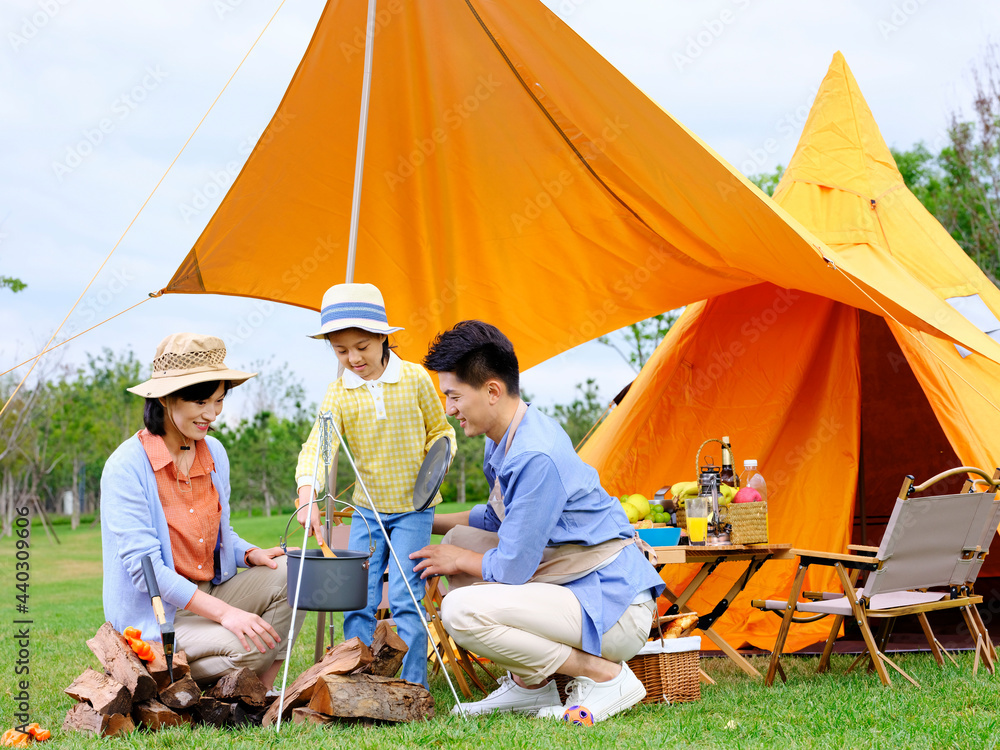 A happy family of three cooks outdoors