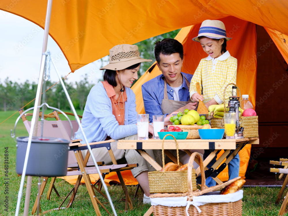 A happy family of three cooks outdoors