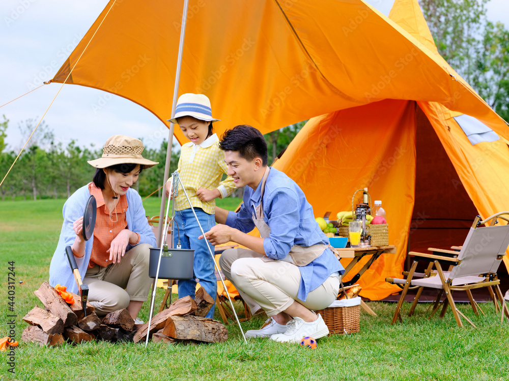 A happy family of three cooks outdoors