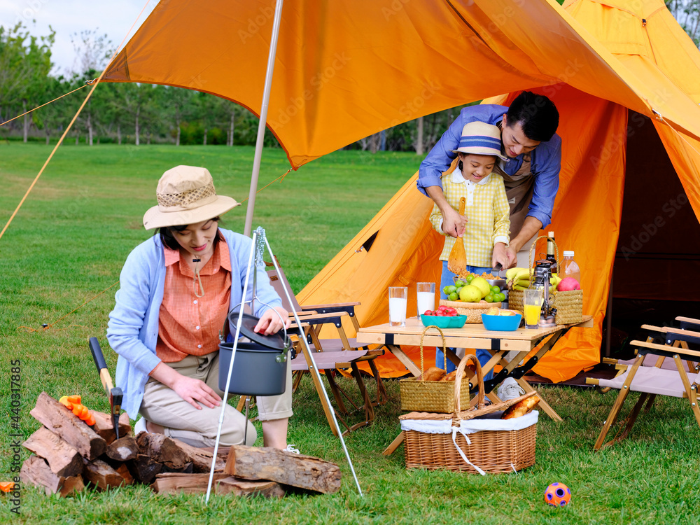 A happy family of three cooks outdoors