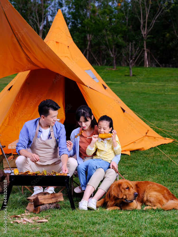 Happy family of three and pet dog barbecue in the park