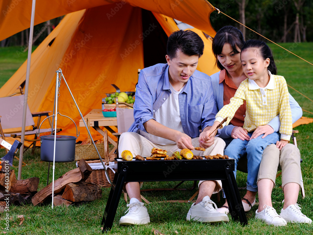 A happy family of three barbecue in the park